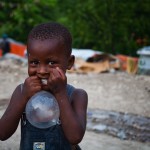 En dreng leger med et kondom i en af de store teltlejre i Petionville, Port au Prince